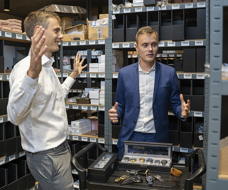 Kasper et Mikkel debout dans l'entrep&ocirc;t avec des bo&icirc;tes de montres et des montres